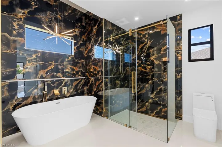 Full bathroom featuring recessed lighting, a shower stall, a freestanding bath, a healthy amount of sunlight, and toilet
