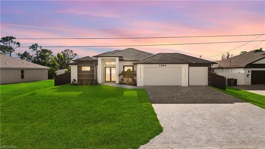 View of front of home featuring fence, stucco siding, decorative driveway, a lawn, and a garage