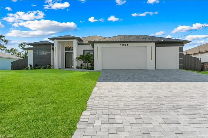 Prairie-style home featuring fence, a front lawn, stucco siding, an attached garage, and decorative driveway