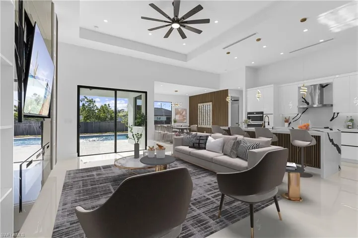 Living area with a ceiling fan, a high ceiling, and recessed lighting