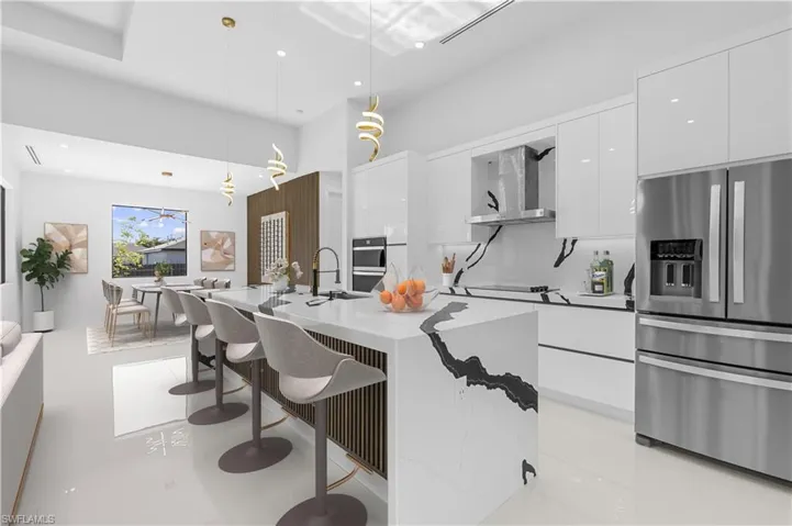 Kitchen featuring wall chimney exhaust hood, modern cabinets, stainless steel refrigerator with ice dispenser, white cabinets, and recessed lighting