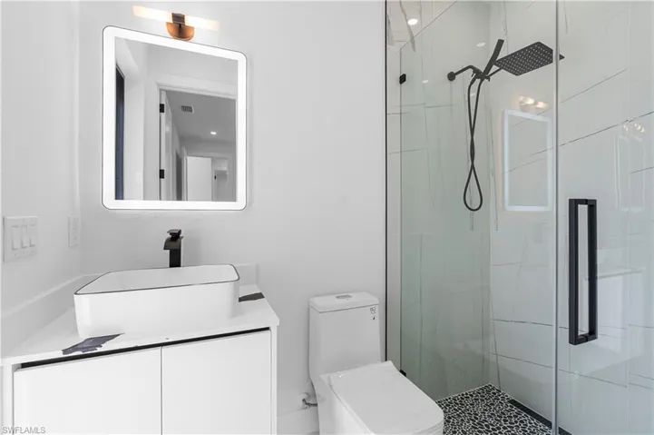 Bathroom featuring vanity, a shower stall, and toilet