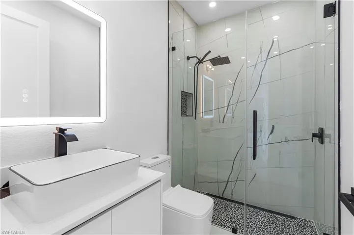Full bathroom with recessed lighting, toilet, vanity, and a stall shower