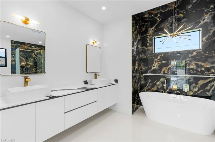 Full bathroom featuring a freestanding bath, a sink, double vanity, and recessed lighting
