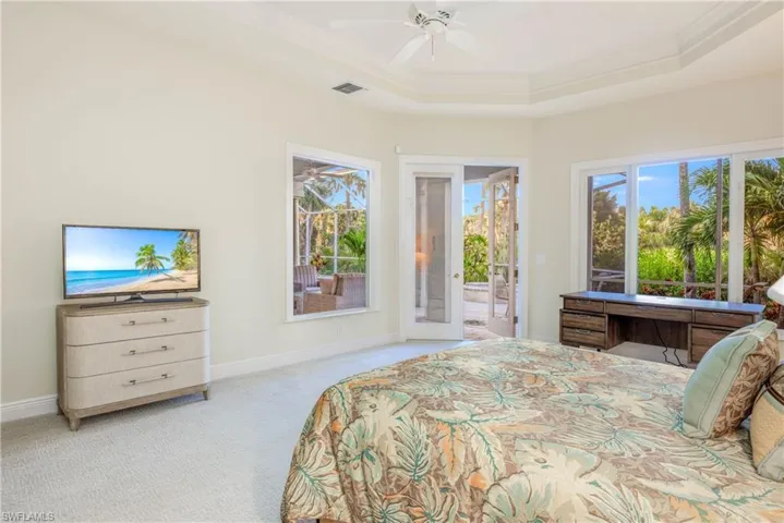 Primary Bedroom features new carpeting and french doors to the covered lanai and pool area