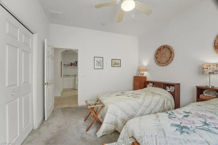 Bedroom with a closet, carpet floors, ceiling fan, and arched walkways