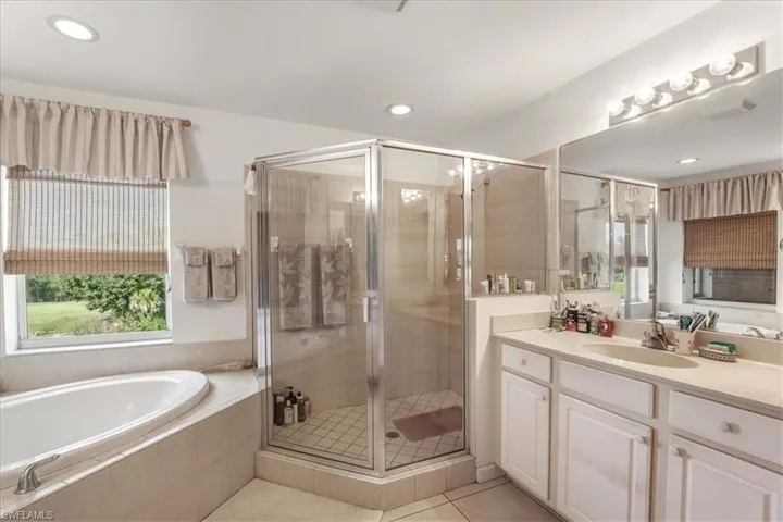Bathroom featuring vanity, a shower stall, a bath, light tile patterned flooring, and recessed lighting