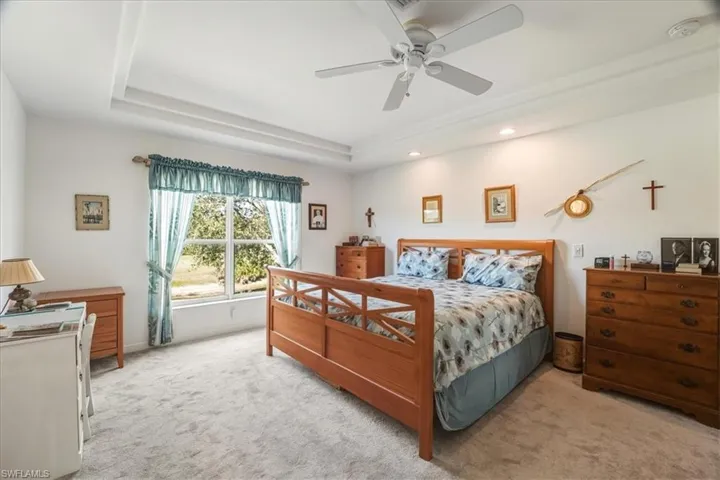 Carpeted bedroom with a tray ceiling and a ceiling fan