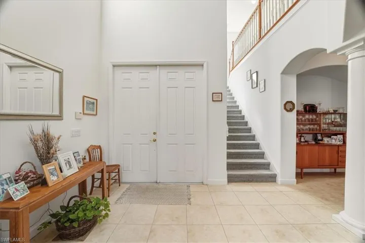 Foyer entrance with a high ceiling, light tile patterned flooring, arched walkways, and ornate columns