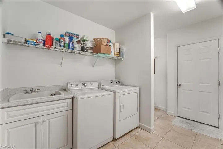 Laundry area featuring washer and dryer, light tile patterned floors, and cabinet space