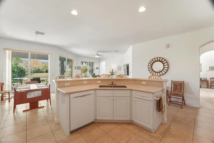 Kitchen with white cabinets, dishwasher, an island with sink, light tile patterned flooring, and recessed lighting