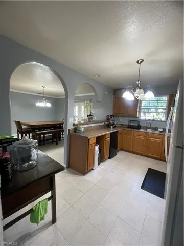 Functional kitchen featuring light-toned tile flooring, honey-toned wood cabinetry, and a speckled countertop