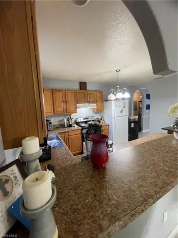 Kitchen featuring wood cabinetry, a built-in oven range with a matching range hood, and a dual-basin sink