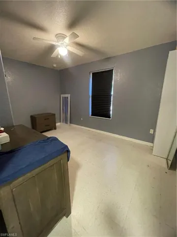 Room with light-toned flooring, featuring a window with dark blinds, a ceiling fan with integrated lighting, and neutral wall tones