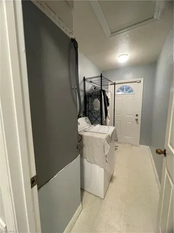 Utility room featuring light blue walls, tile-finish flooring, a flush-mount ceiling light, and a white exterior door with a decorative glass insert