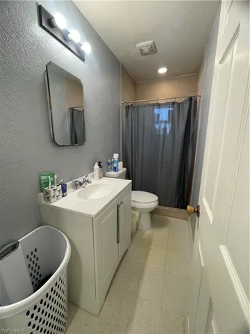 Bathroom featuring a white vanity with integrated sink, chrome faucet, wall-mounted mirror, and overhead lighting fixture