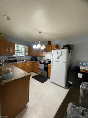 Kitchen featuring light wood-finish cabinetry, tile flooring, and a stainless steel range