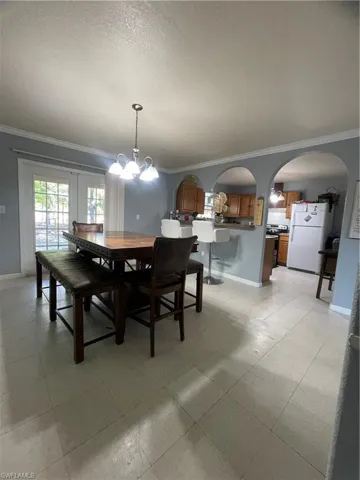Dining area featuring light-toned tile flooring and crown molding