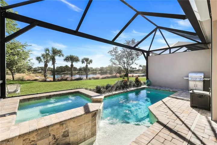 View of pool with glass enclosure, a sunroom, a patio area, a yard, and a water view