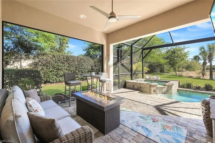 View of patio / terrace featuring a sunroom, a ceiling fan, a pool with connected hot tub, glass enclosure, and an outdoor living space with a fire pit