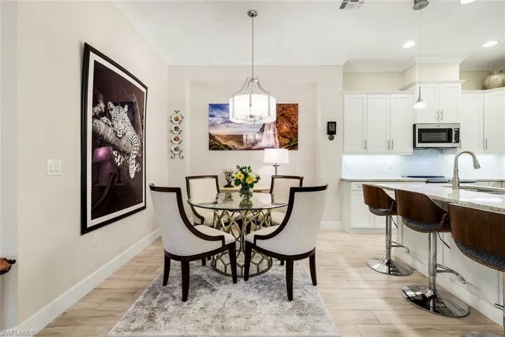 Dining space with light wood finished floors, crown molding, and recessed lighting