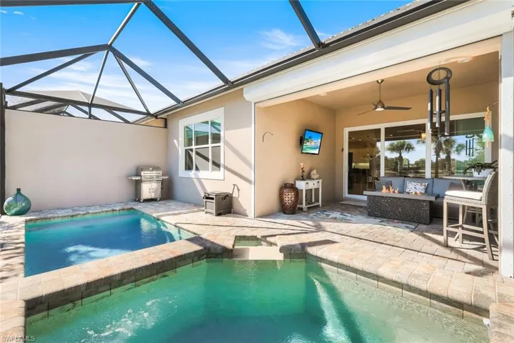 View of swimming pool featuring glass enclosure, a sunroom, a patio area, and a pool with connected hot tub
