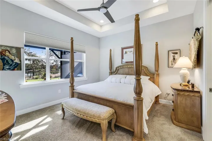 Bedroom with carpet floors, ceiling fan, a tray ceiling, and recessed lighting