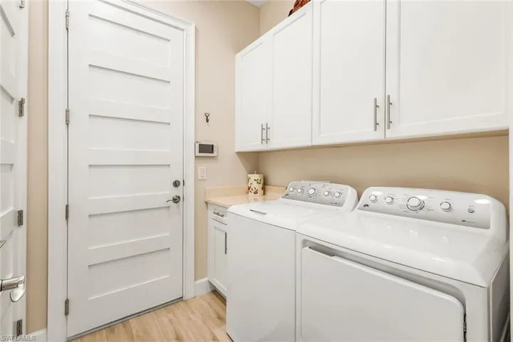 Laundry area with light wood-style floors, cabinet space, and washer and dryer