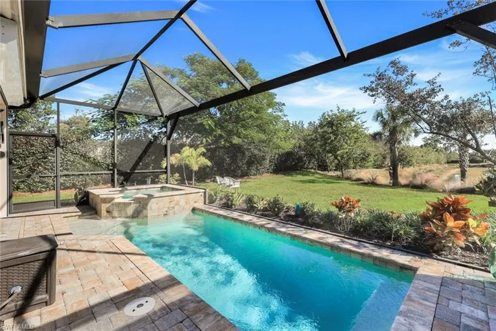 View of swimming pool featuring a lanai, a patio area, a sunroom, a lawn, and a pool with connected hot tub