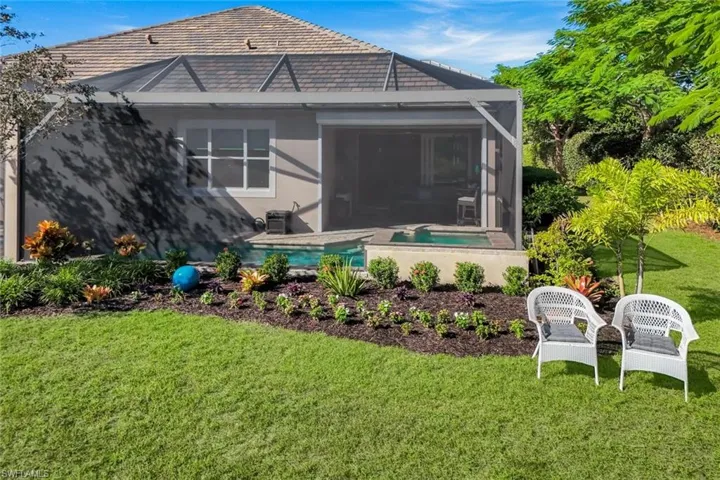 Rear view of house with a lawn, glass enclosure, a sunroom, an outdoor pool, and stucco siding