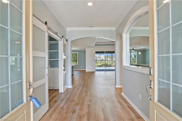 Hallway featuring light hardwood / wood-style floors, a barn door, and crown molding
