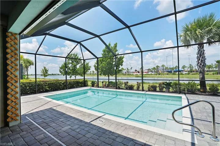 View of pool featuring screened enclosure, a patio area, and a water view