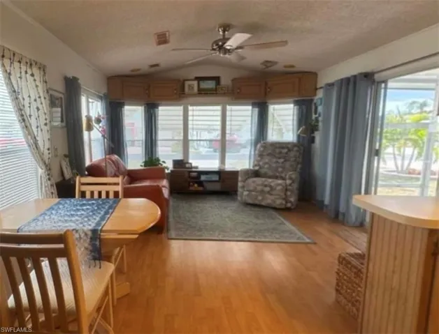 Sunroom / solarium with a textured ceiling, a healthy amount of sunlight, wood finished floors, and lofted ceiling
