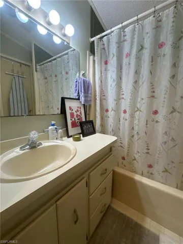 Bathroom featuring shower / bath combo, ornamental molding, tile patterned floors, and vanity
