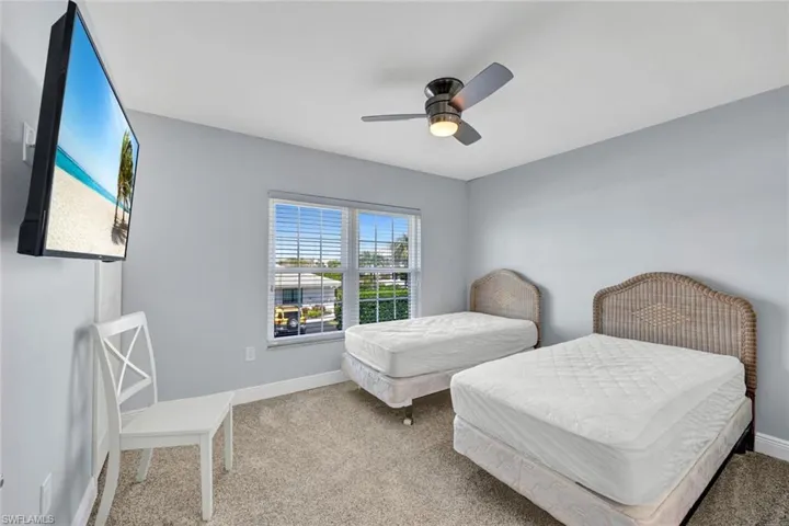 Carpeted room featuring a ceiling fan with integrated lighting, a large window with blinds, and light-toned walls