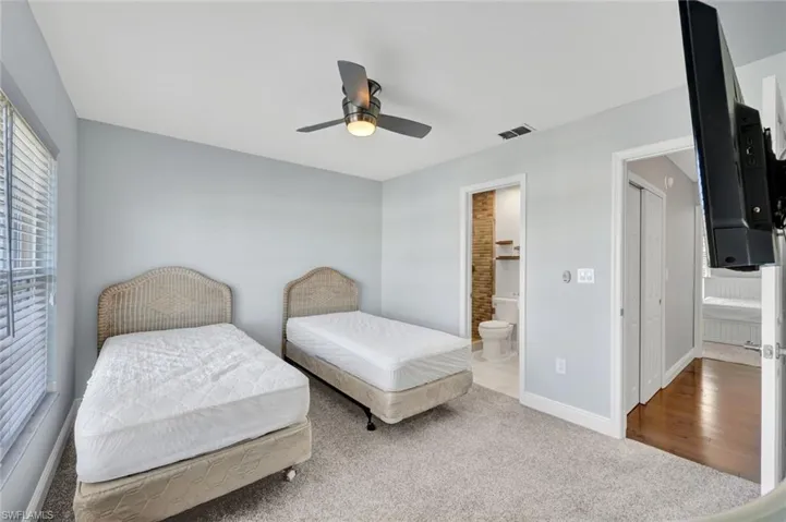 Carpeted room with light blue walls and a vaulted ceiling featuring a ceiling fan