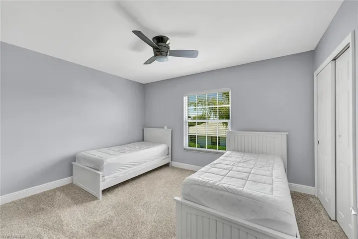 Carpeted room featuring light gray walls, a window with horizontal blinds, a ceiling fan with light, and bi-fold closet doors