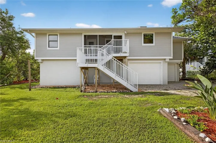 Front view of property with stairs, a lawn, a balcony, and a garage