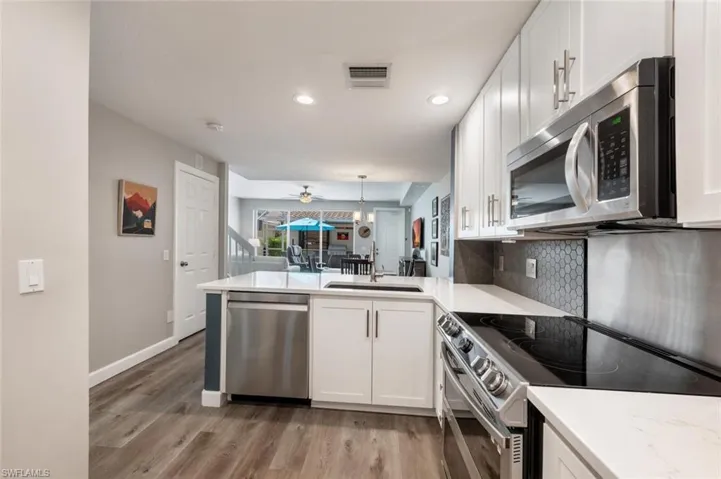 Kitchen with stainless steel appliances, breakfast nook and view of living & dining area.