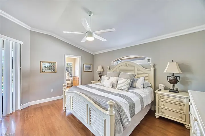 Bedroom with crown molding, vaulted ceiling, dark wood finished floors, multiple windows, and ceiling fan