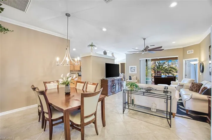 Dining space with crown molding, recessed lighting, a ceiling fan, a chandelier, and light tile patterned flooring