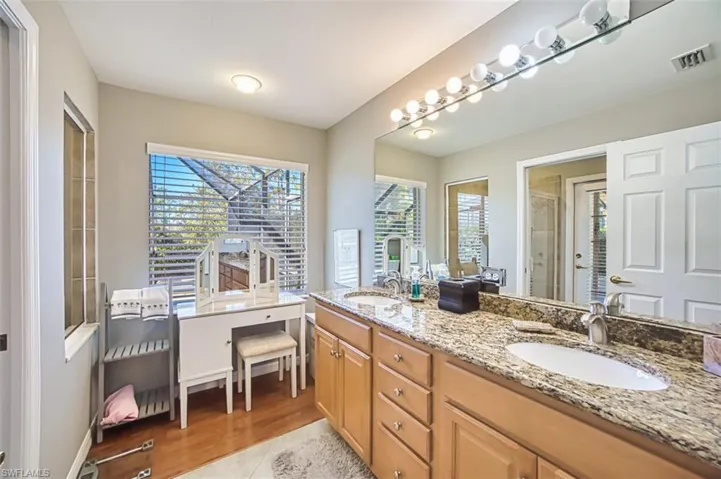 Full bathroom with double vanity, plenty of natural light, a stall shower, and light wood-type flooring