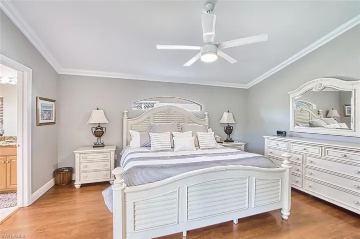 Bedroom with ornamental molding, ensuite bath, light wood-style flooring, and ceiling fan