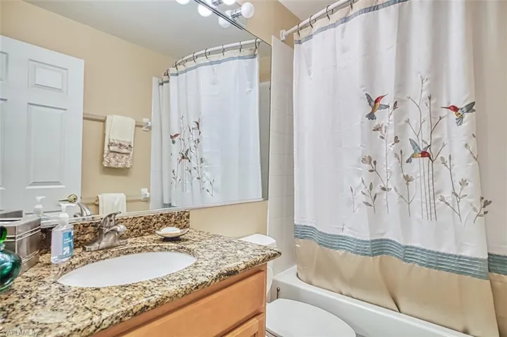 Bathroom featuring vanity and shower / bath combination with curtain