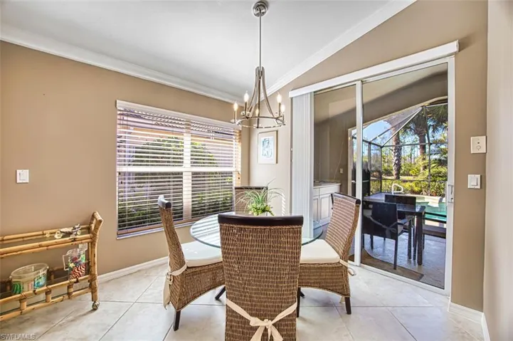 Dining area featuring lofted ceiling, a chandelier, ornamental molding, a sunroom, and tile patterned flooring