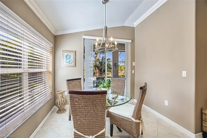 Dining area with ornamental molding, a chandelier, tile patterned floors, and vaulted ceiling
