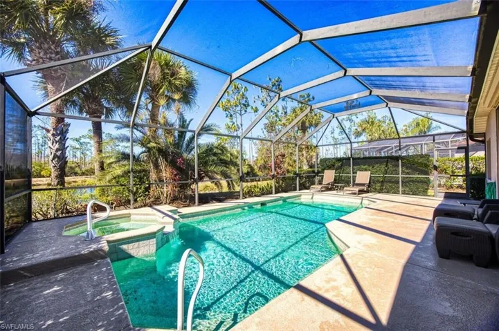 View of pool with a pool with connected hot tub, a sunroom, a patio, and glass enclosure