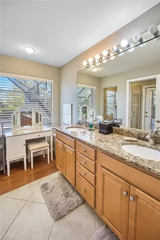 Full bath with double vanity, light tile patterned floors, and a shower stall