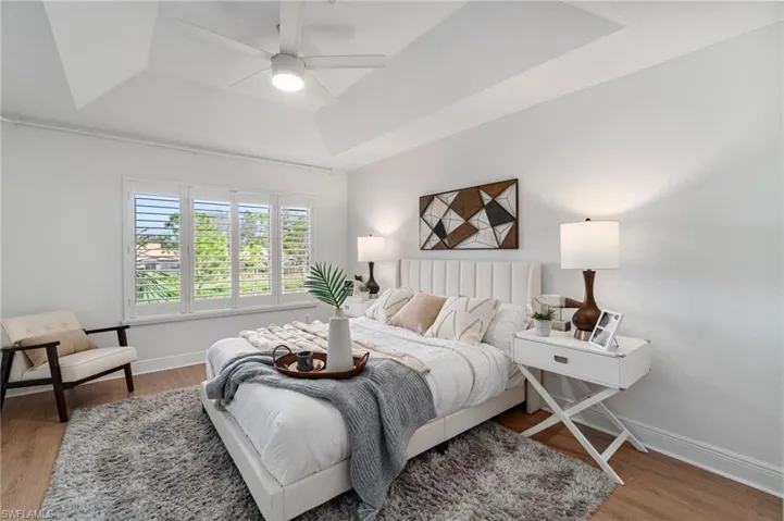 Filled with natural light, the primary bedroom features a tray ceiling creating a spacious and relaxing atmosphere.