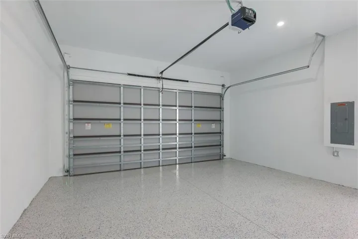 Spacious garage featuring a sectional garage door, light-colored epoxy flooring, and recessed lighting